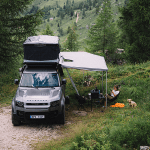 Coche 4x4 con tienda de techo de acampada en el bosque