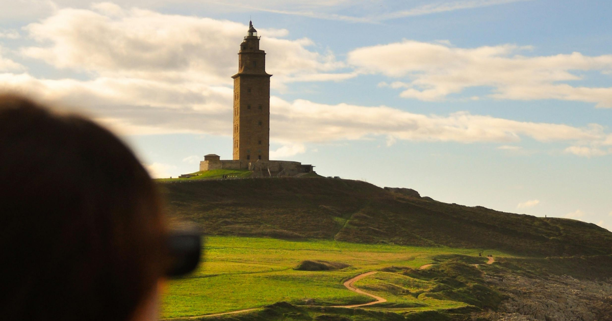 Chica con gafas de sol mirando a la Torre de Hércules en La Coruña.