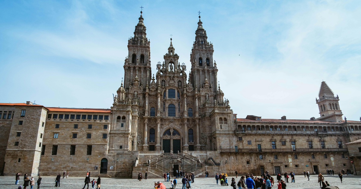 Plaza con genete caminando en frente de la catedral de Santiago de Compostela.