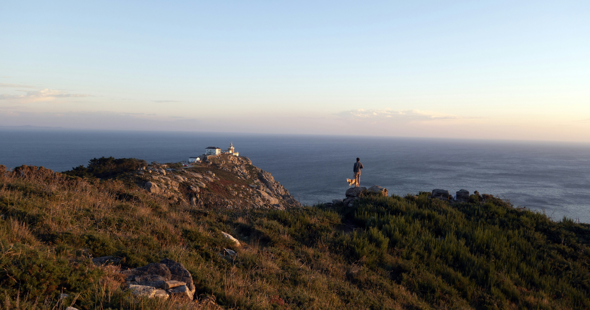 Persona en una colina con vistas al oceano en Finisterre Galicia.