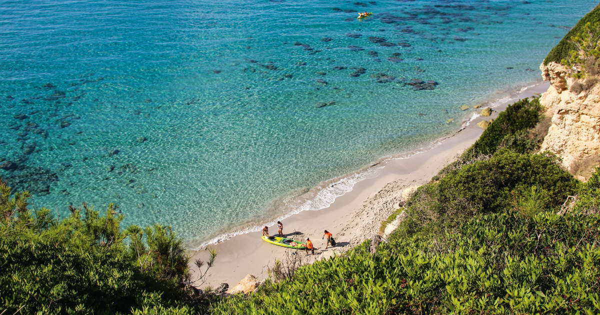 Personas con Kayak en una playa de Menorca. Ruta Camper en Menorca