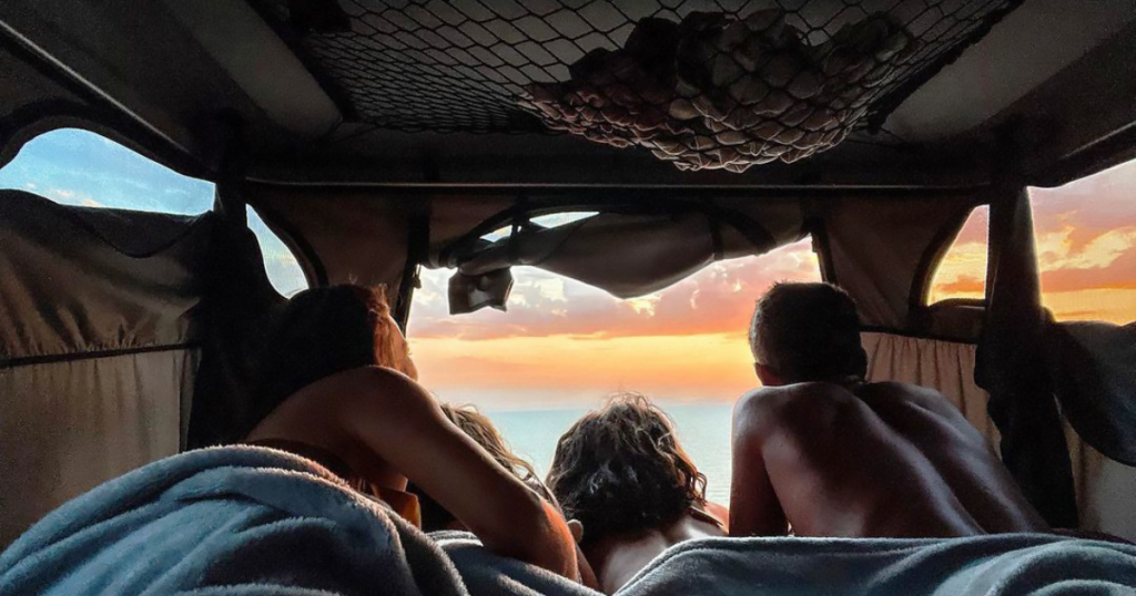 Familia dentro d euna tienda de techo observando amanecer