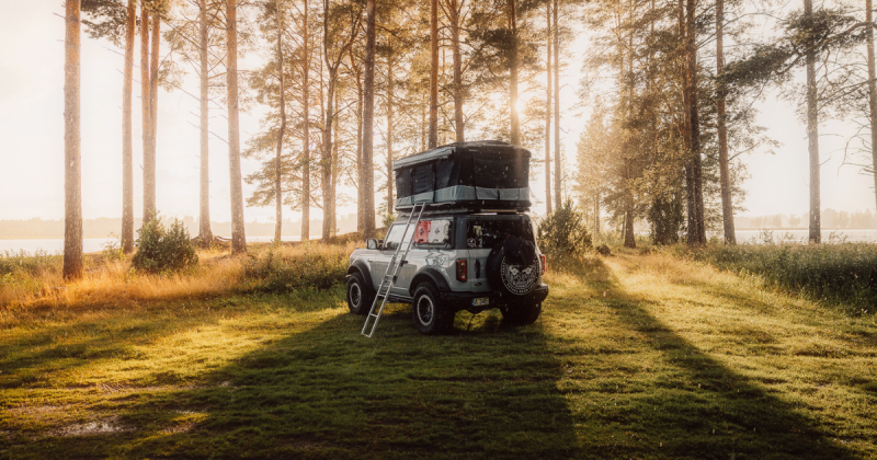 coche estilo 4x4 con tienda de techo en bosque